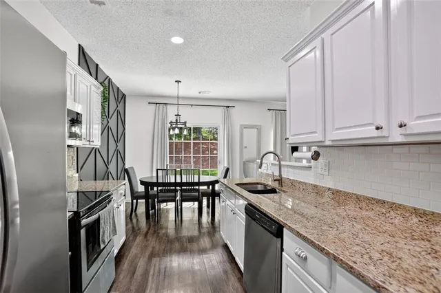 a kitchen with granite countertop a sink appliances cabinets and wooden floor