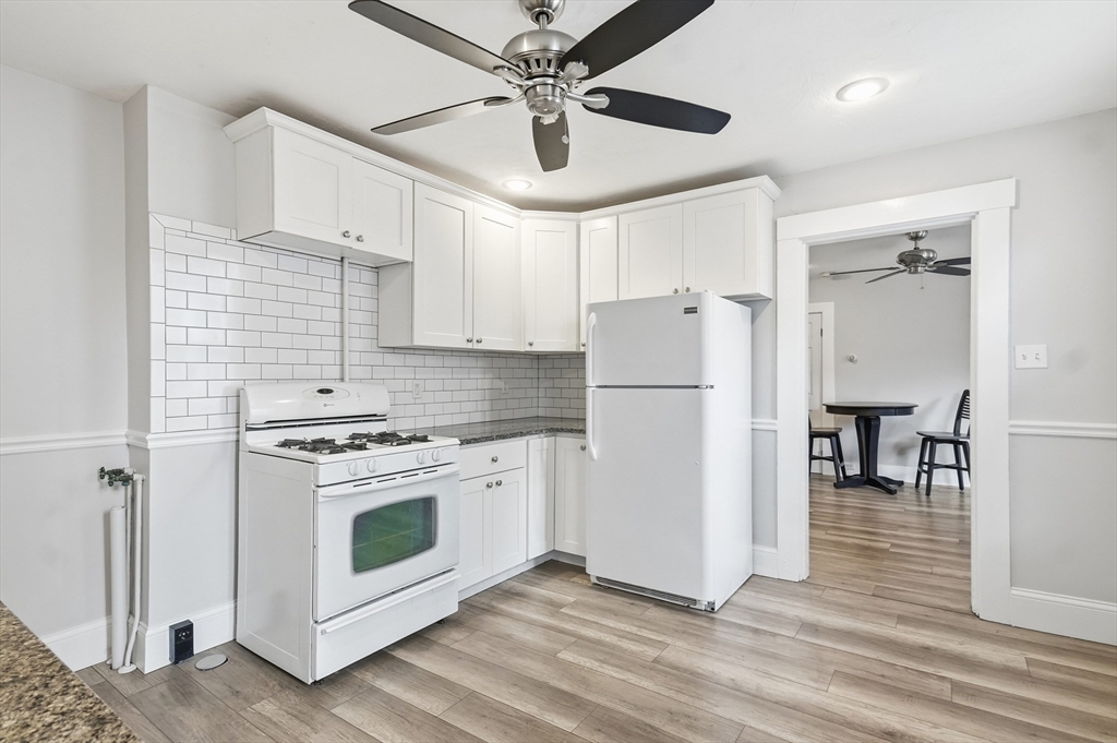 163-165 Chestnut Street Waltham, MA 02453 - Photo 6 of 41 a kitchen with a refrigerator a stove top oven and a ceiling fan