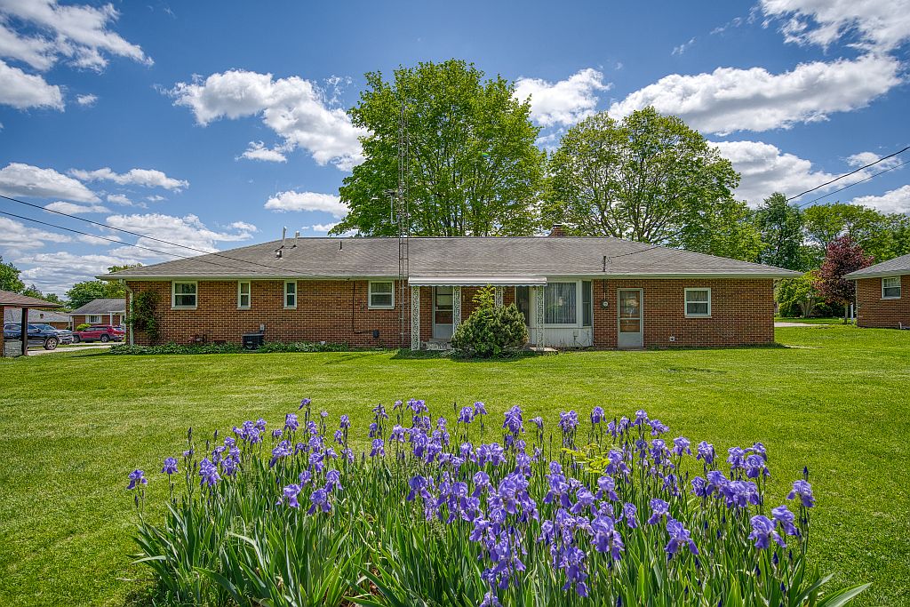 324 Beckenham Road Englewood, OH 45322 - Photo 22 of 26 This ranch-style home features a classic brick exterior and an expansive green lawn, offering a serene outdoor space.