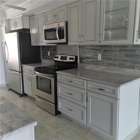 a kitchen with stainless steel appliances granite countertop white cabinets a refrigerator and a stove