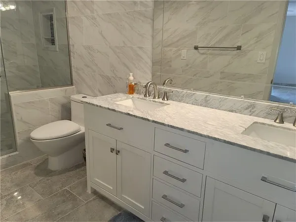 a bathroom with a granite countertop toilet sink and mirror