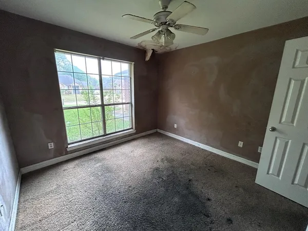 en empty room with windows and ceiling fan