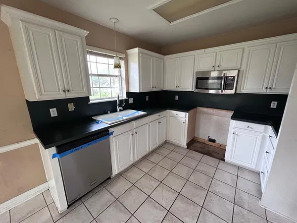 a kitchen with a sink a stove top oven and white cabinets