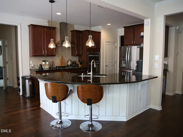 a kitchen with stainless steel appliances kitchen island granite countertop a table chairs and a refrigerator