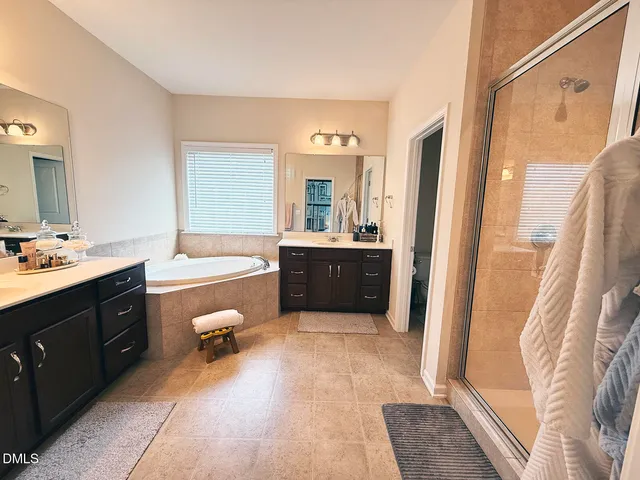a spacious bathroom with a double vanity sink a mirror and a bathtub