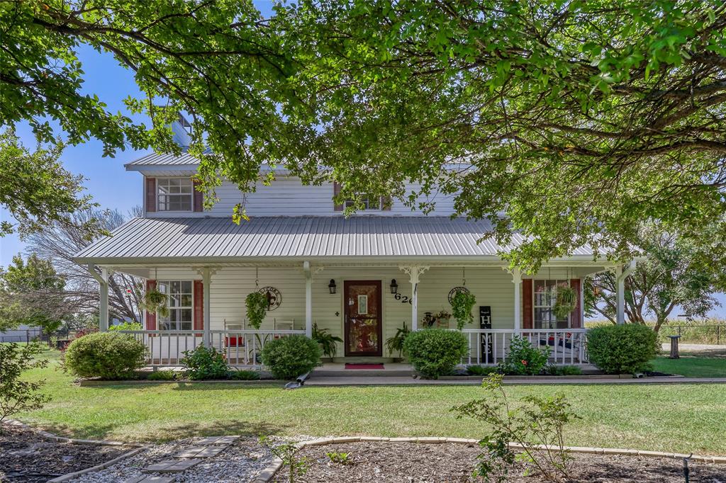 626 Epps Road Palmer, TX 75152 - Photo 1 of 27 Two-story white siding residence featuring a metal roof, a full-width covered front porch with white railings, and red window shutters