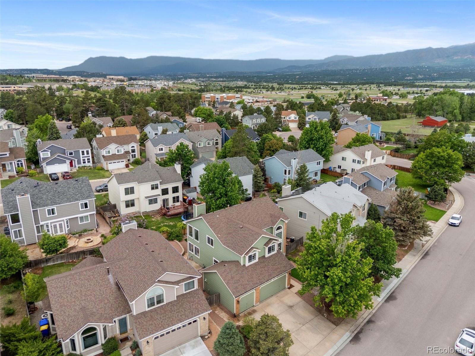 2035 Springcrest Road Colorado Springs, CO 80920 - Photo 4 of 39 an aerial view of a city with lots of residential buildings and mountain view in back
