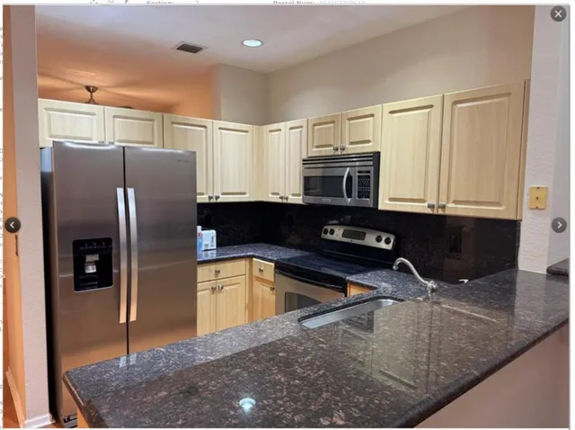 a kitchen with stainless steel appliances granite countertop a sink a stove and a refrigerator