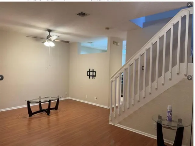 a view of a livingroom with wooden floor and a ceiling fan