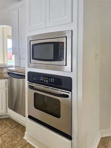a kitchen with granite countertop white cabinets and stainless steel appliances