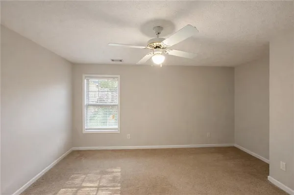 an empty room with a window and a fan