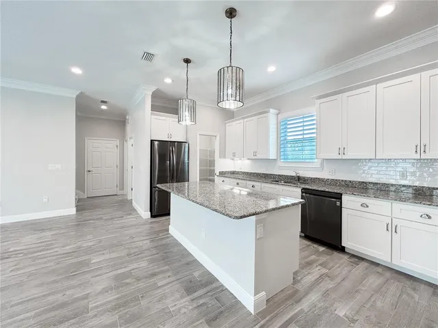 a kitchen with stainless steel appliances granite countertop a stove and refrigerator a sink with wooden floors