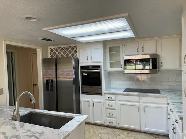 a kitchen with stainless steel appliances kitchen island a refrigerator sink and cabinets