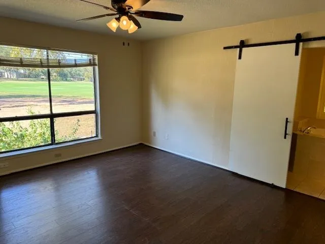 an empty room with wooden floor fan and windows