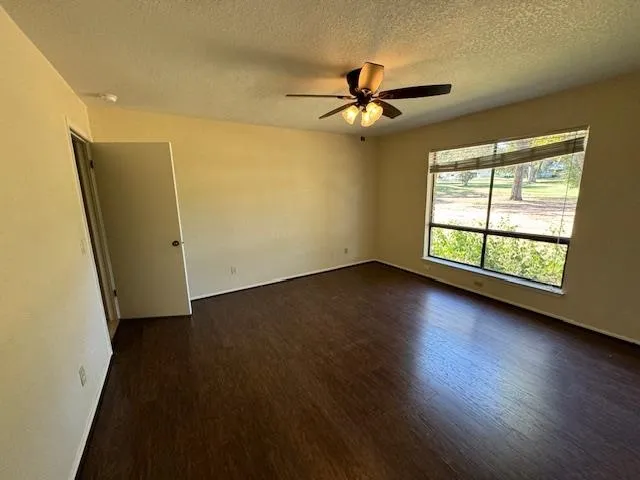 a view of a livingroom with wooden floor a ceiling fan and windows