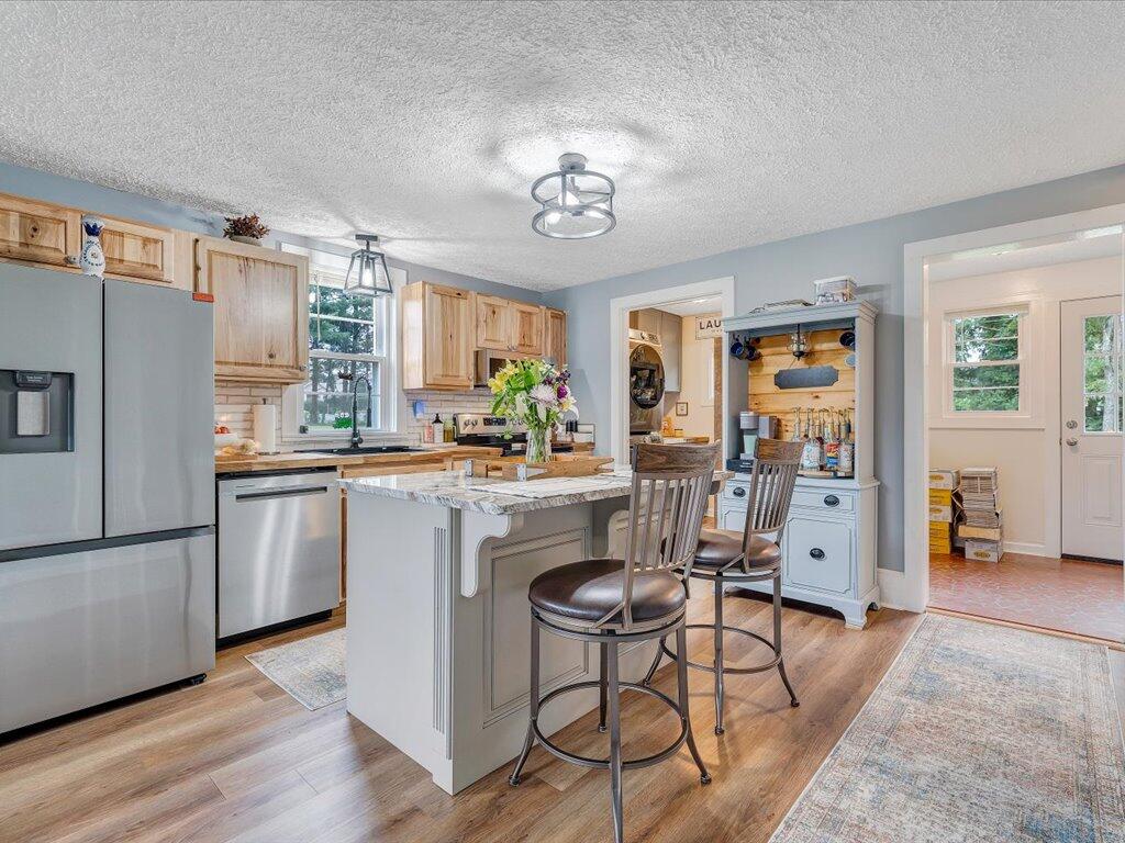 214 Spring Road Patrick Springs, VA 24133 - Photo 9 of 49 a kitchen with stainless steel appliances granite countertop a refrigerator a stove a sink a dining table and chairs with wooden floor