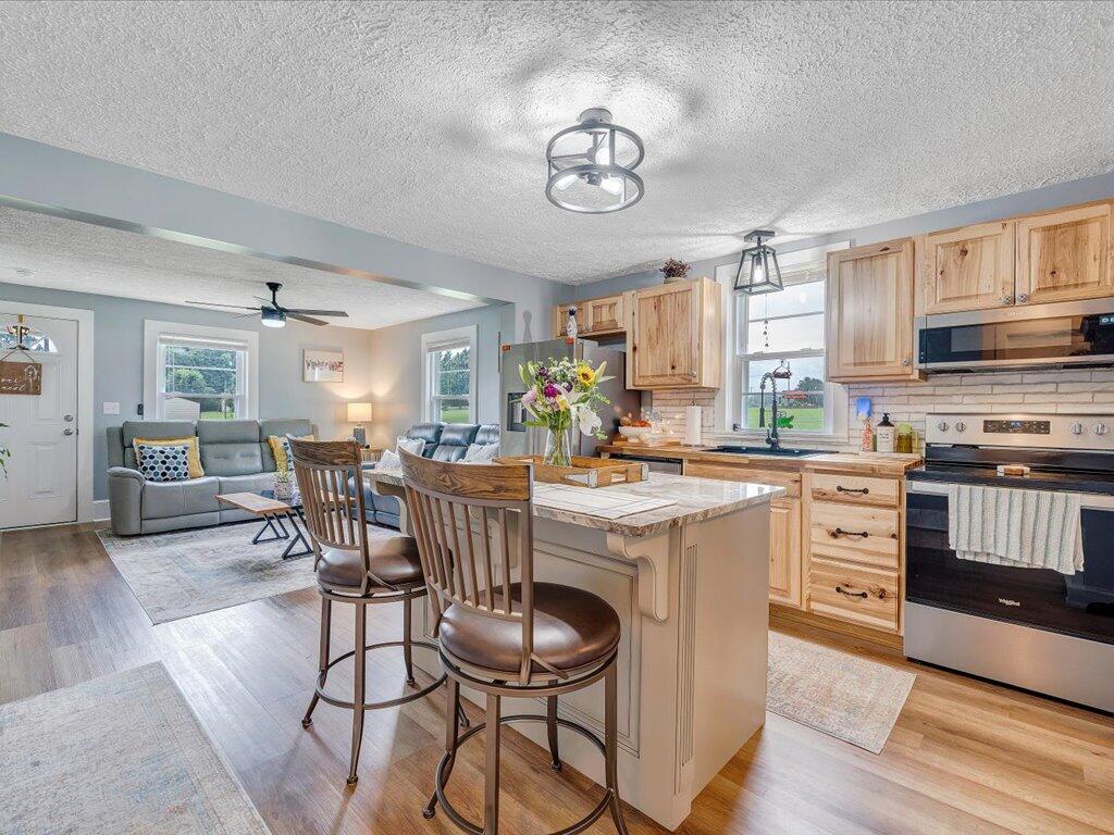 214 Spring Road Patrick Springs, VA 24133 - Photo 10 of 49 a kitchen with stainless steel appliances granite countertop a stove top oven a sink dishwasher a dining table and chairs with wooden floor