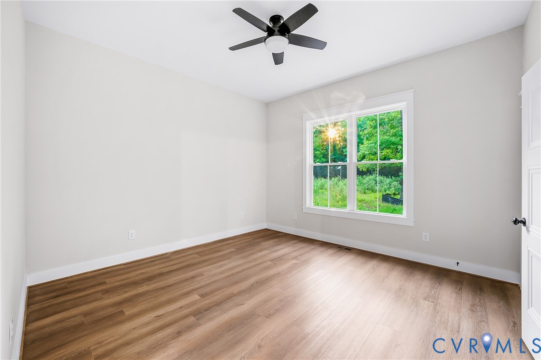 8299 Pamlico Road Ashland, VA 23005 - Photo 19 of 35 an empty room with wooden floor a ceiling fan and windows