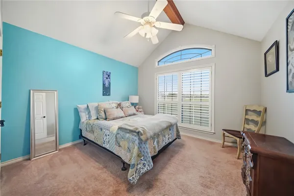 a bedroom with a bed a desk and chair with windows