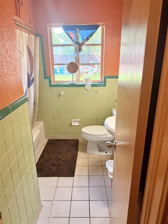 9918 Constance Street Dallas, TX 75220 - Photo 12 of 13 Bathroom with tile walls, light tile patterned floors, shower / bath combo, wainscoting, and a textured wall