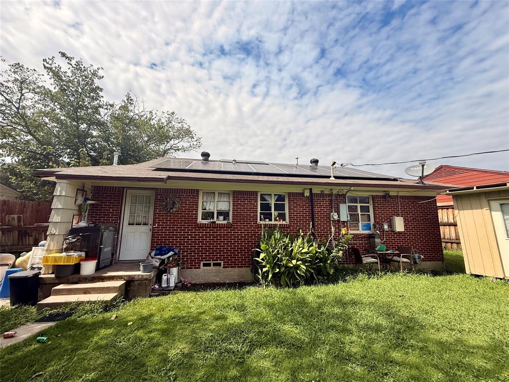 9918 Constance Street Dallas, TX 75220 - Photo 4 of 13 Rear view of property featuring roof mounted solar panels and brick siding