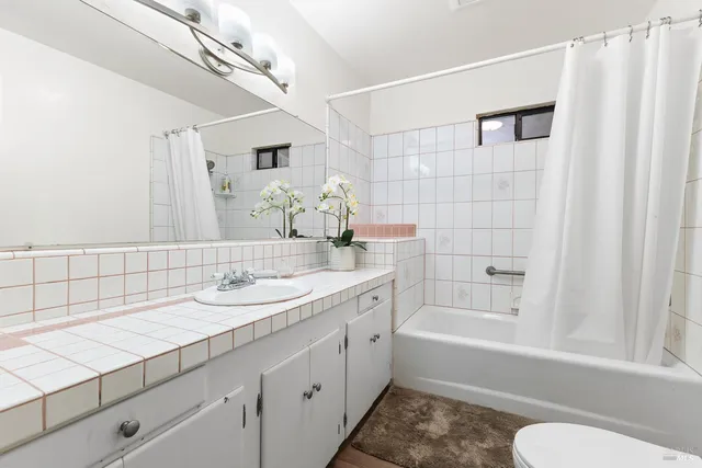 a bathroom with a granite countertop sink a toilet and bathtub