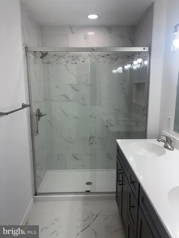 a bathroom with a shower sink vanity and mirror