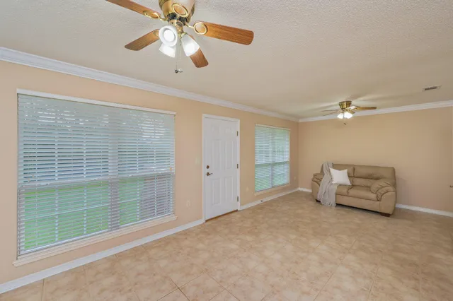 a view of an empty room and chandelier fan