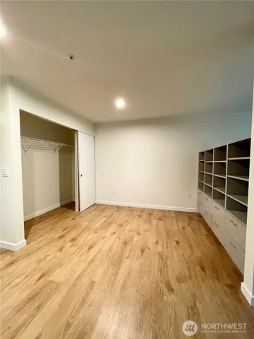 a view of an empty room with wooden floor and windows