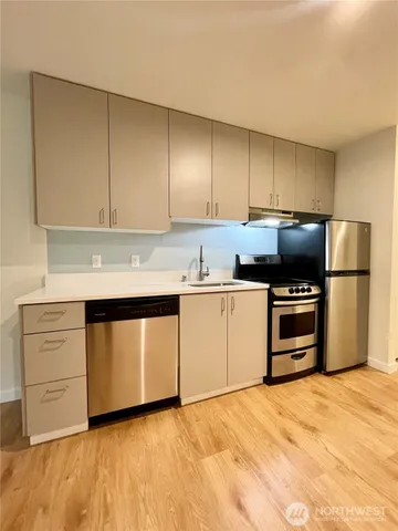 a kitchen with granite countertop a refrigerator stove and cabinets