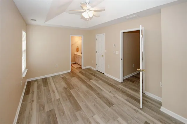 an empty room with wooden floor and fan