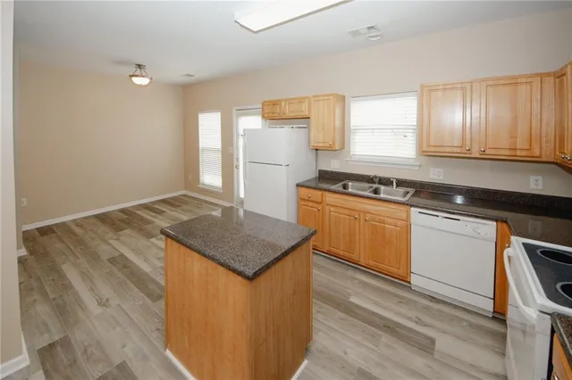 a kitchen with granite countertop a stove a sink and white cabinets with wooden floor