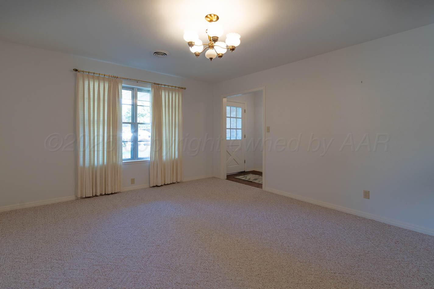 6207 Elmhurst Road Amarillo, TX 79106 - Photo 5 of 21 an empty room with windows and chandelier fan