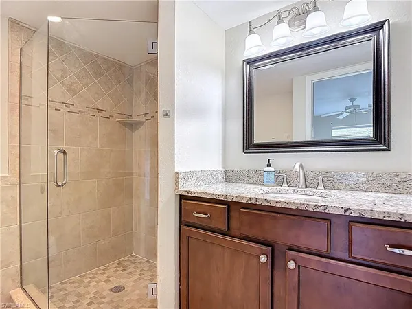 a bathroom with a granite countertop sink a mirror and shower