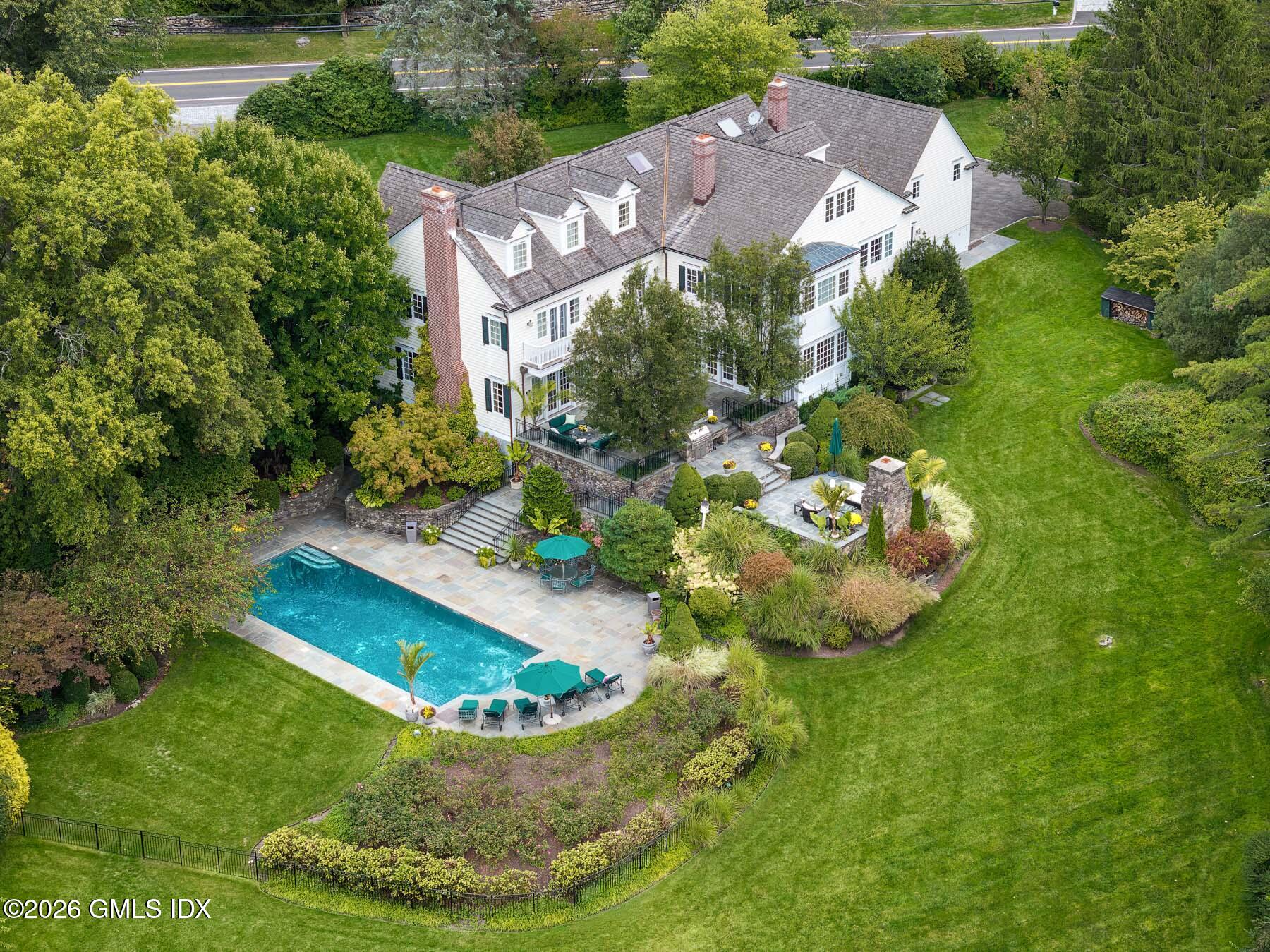 174 Round Hill Road Greenwich, CT 06831 - Photo 23 of 27 a view of a house with a swimming pool and lawn chairs under an umbrella