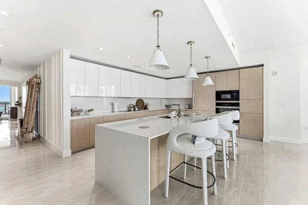 a kitchen with kitchen island a dining table chairs stainless steel appliances and cabinets