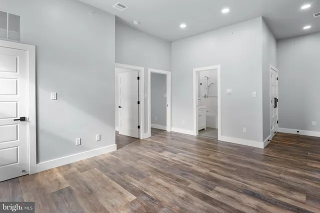 a view of an empty room with wooden floor and closet area
