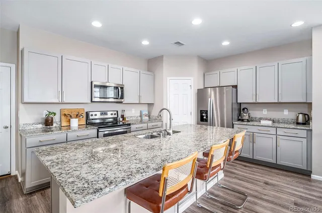 a kitchen with stainless steel appliances granite countertop a sink a stove and a wooden cabinets