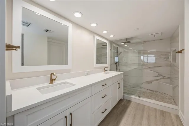 a bathroom with a double vanity sink mirror and shower