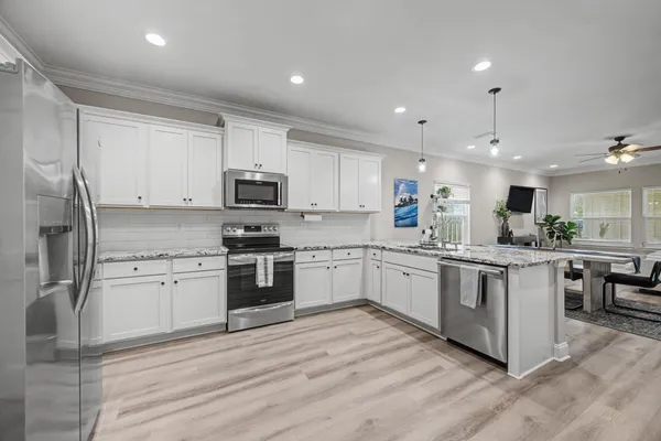 a kitchen with granite countertop a refrigerator stove top oven and sink