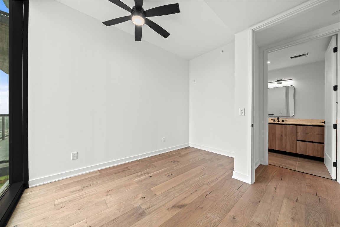 84 East Avenue, Unit 2403 Austin, TX 78701 - Photo 5 of 29 Representative Photo. Primary bedroom with wood flooring and a ceiling fan