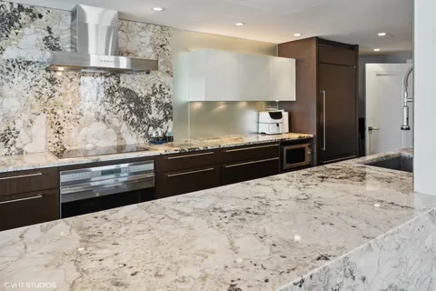 a kitchen with stainless steel appliances kitchen island granite countertop a refrigerator and a stove top oven