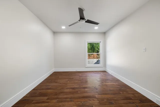 a view of an empty room with a window and wooden floor