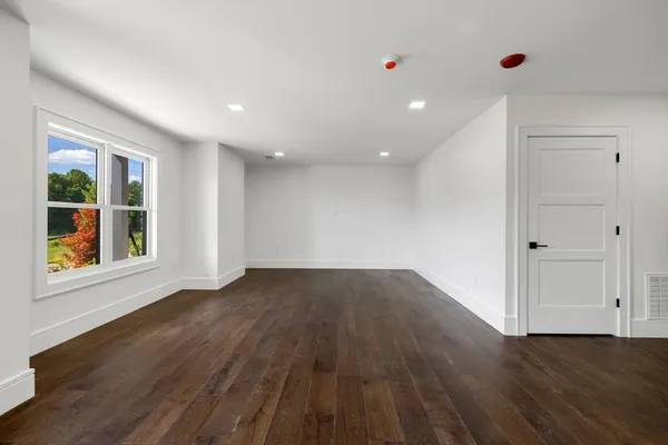 a view of an empty room with wooden floor and window