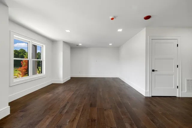 a view of an empty room with wooden floor and window