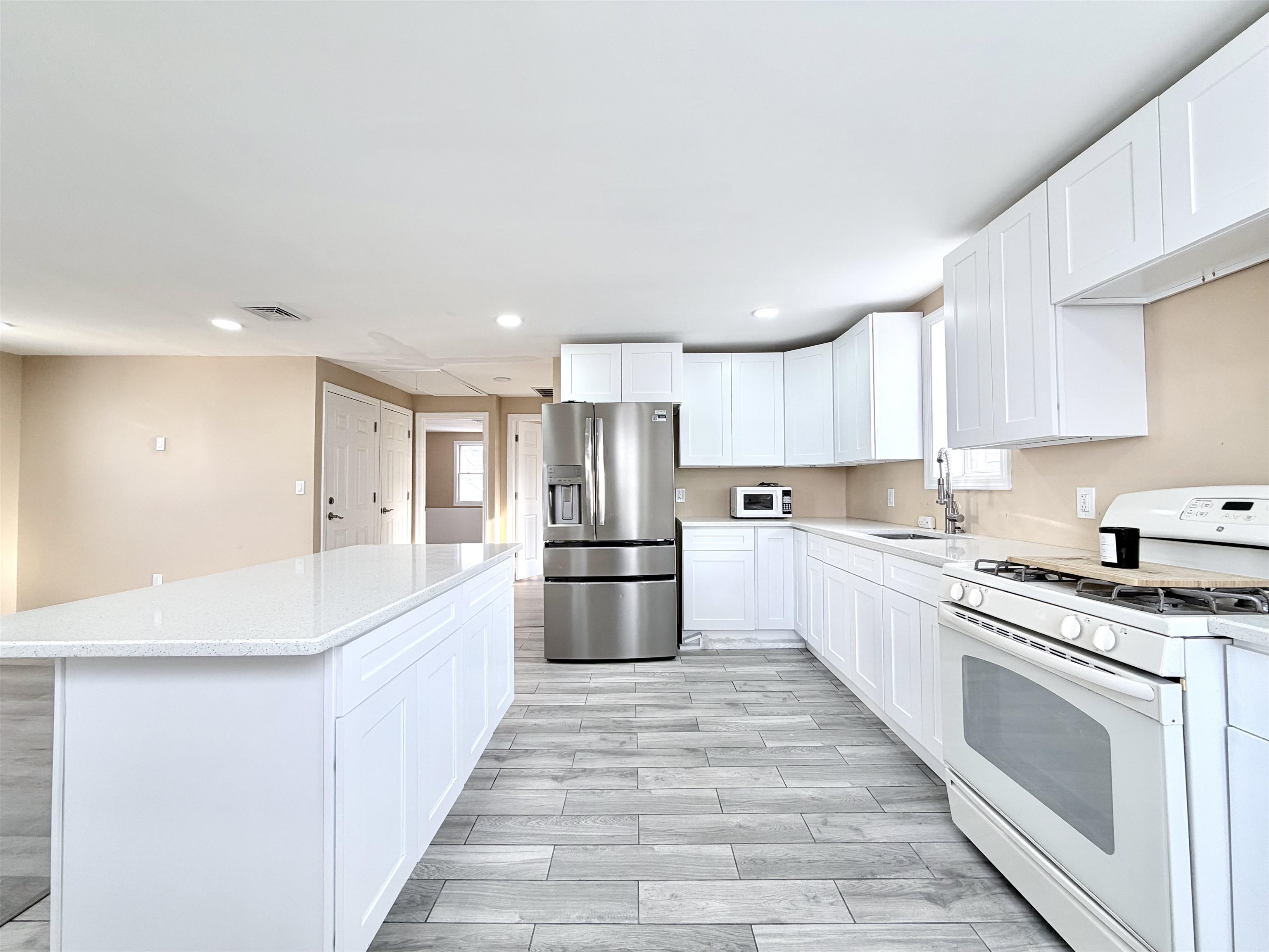 1572 Summit Avenue, Unit 2 Hillside, NJ 07205 - Photo 3 of 20 a large kitchen with a stove top oven a refrigerator and white cabinets