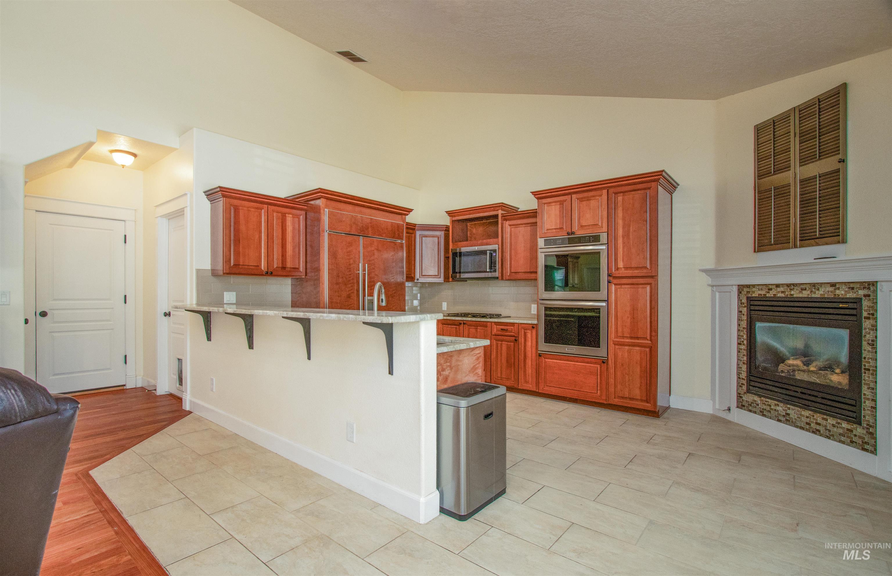 892 South Capitola Way Boise, ID 83712 - Photo 12 of 34 Spacious kitchen featuring wood cabinetry, integrated stainless steel appliances, a breakfast bar, and light-toned tile flooring
