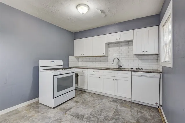 a kitchen with granite countertop white cabinets sink and stainless steel appliances
