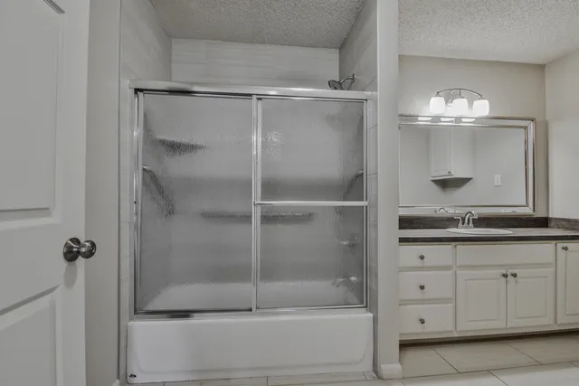 a bathroom with a granite countertop sink mirror and shower