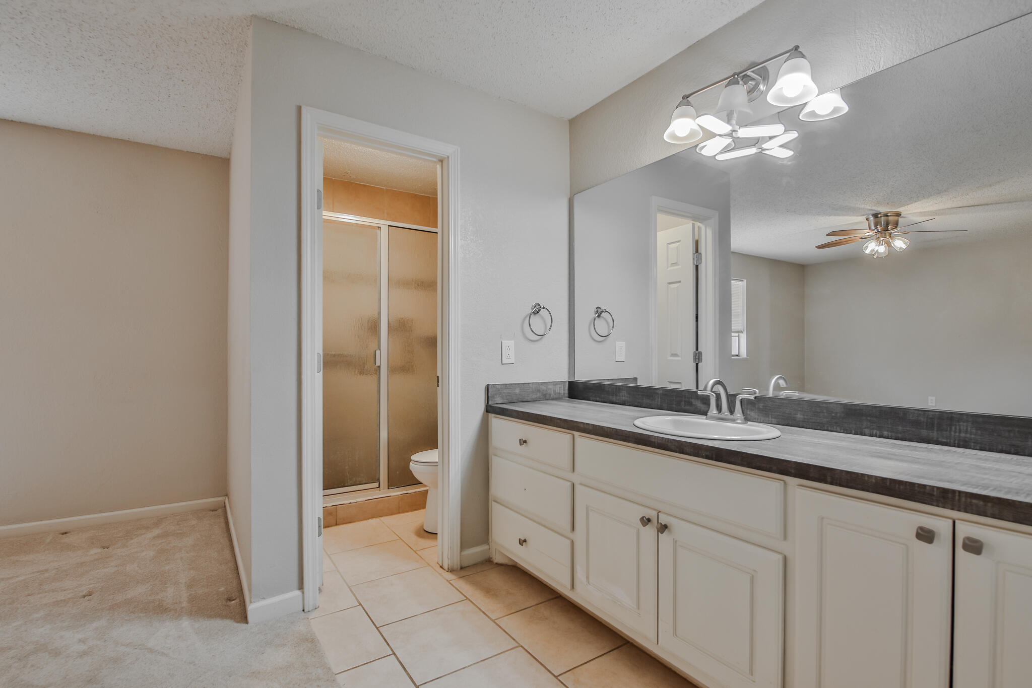 5437 45th Street Lubbock, TX 79414 - Photo 27 of 52 a spacious bathroom with a granite countertop sink a mirror and a shower